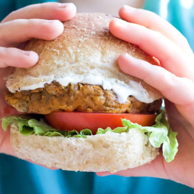 Child Holding Lentil Burger in Bun