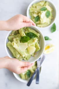 Child Holding Broccoli Pesto Pasta in Bowl