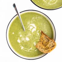 Courgette Soup in Bowl Topped with Cream and Served with Bread.