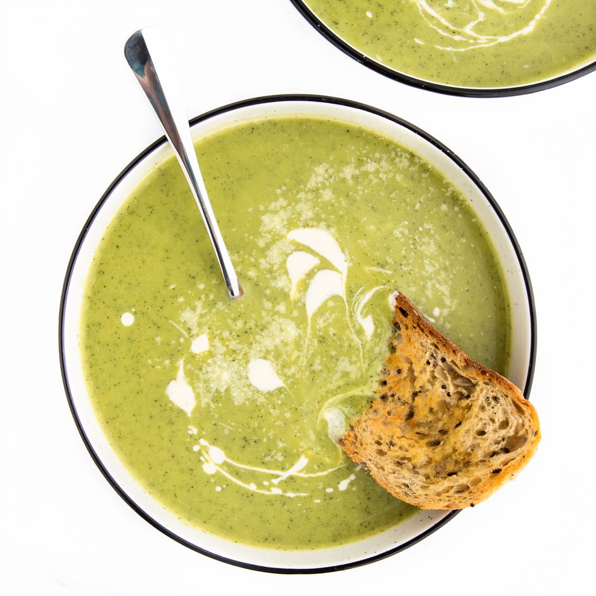 Courgette Soup in Bowl Topped with Cream and Served with Bread.