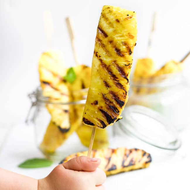 Child Holding Grilled Pineapple Spear on a Stick