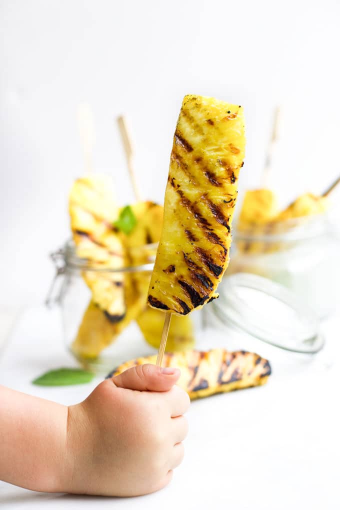 Child Holding Grilled Pineapple Spear on a Stick