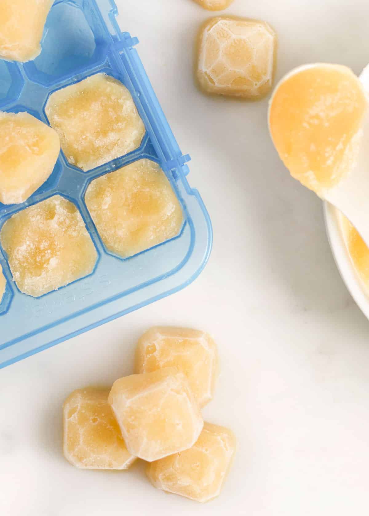 Apple Puree Frozen in Ice Cube Tray with Some Frozen Cubes Removed and Stacked in Pile.