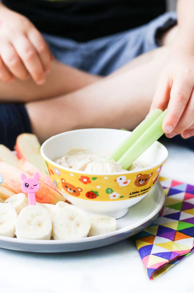 Child Dipping Celery into Peanut Butter Dip