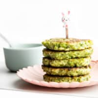 Stack of Broccoli Fritters on Plate with Dip in Background.