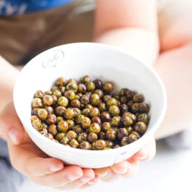 Child holding bowl of roasted peas