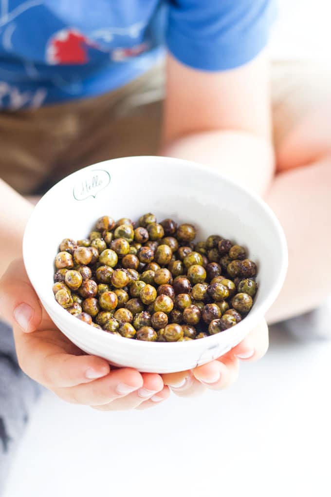 Child holding bowl of roasted peas