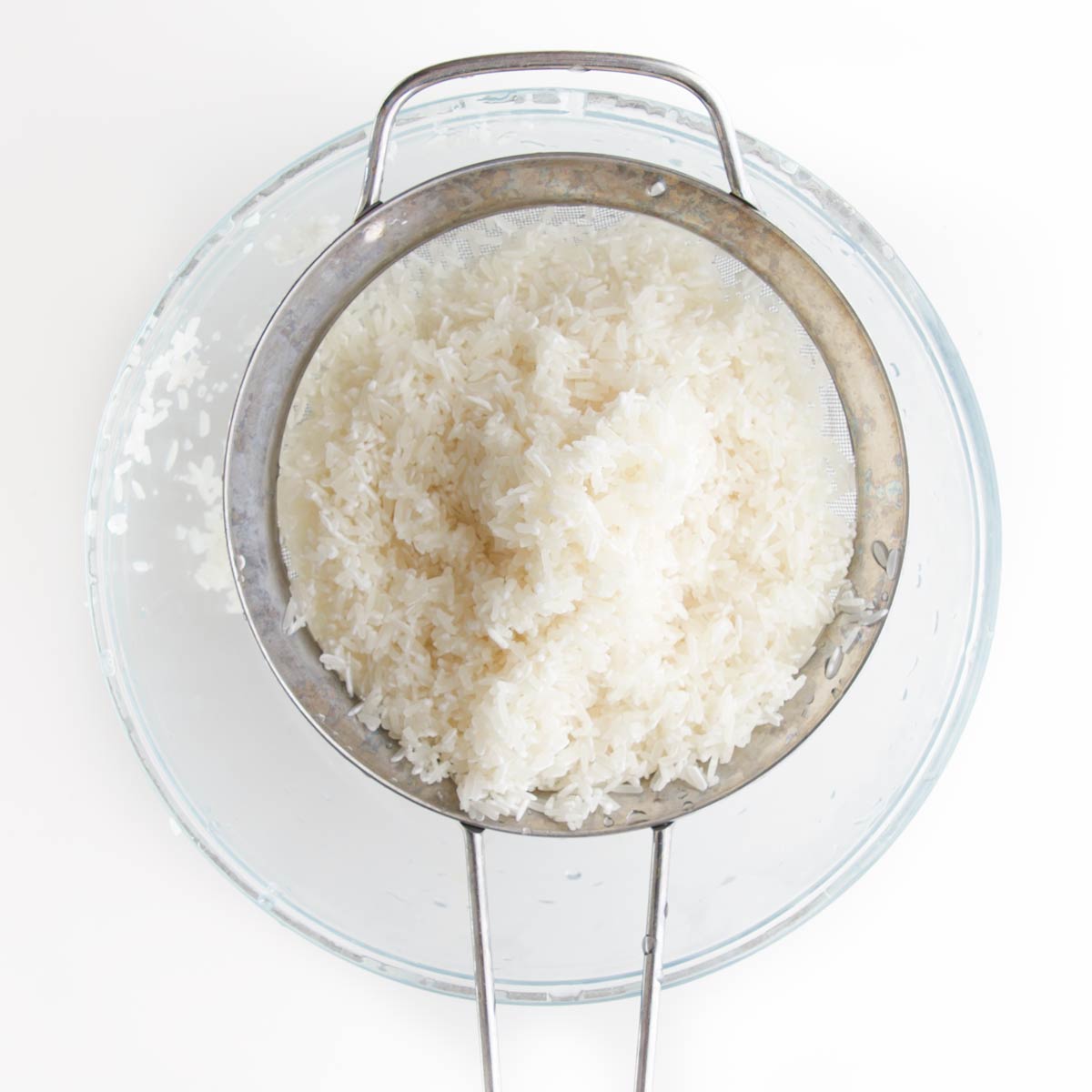 Washed Jasmine Rice in Sieve Over Glass Bowl.