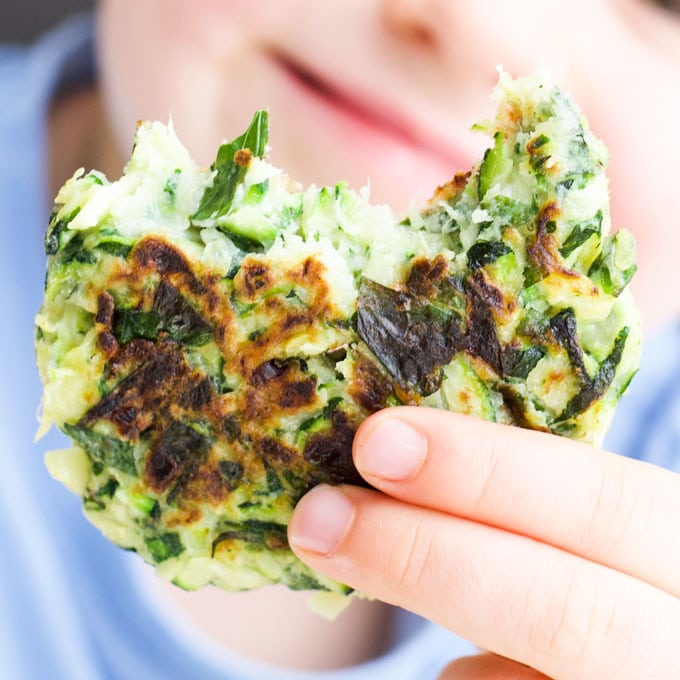 Child Holding Zucchini Fritter with Bite Out of It