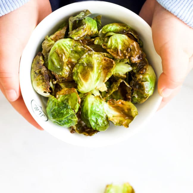 Child Holding Bowl of Brussels Sprouts Chips