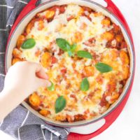 Child Placing Basil Onto a Gnocchi Bake