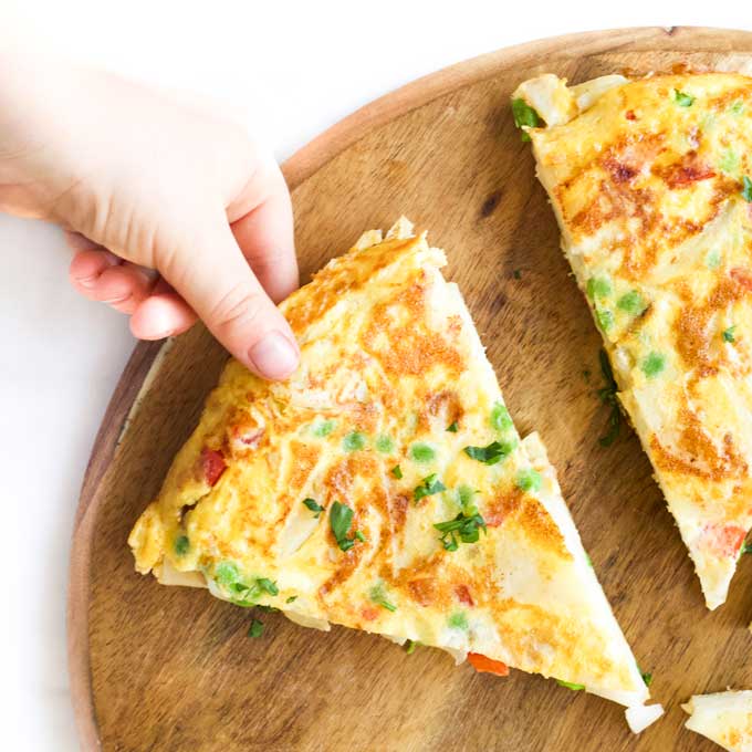 Child Grabbing Slice of Spanish Omelette with Added Veggies