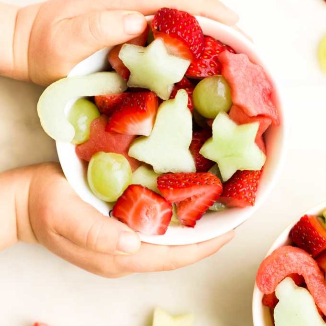 Child Holding a Bowl of Christmas Fruit Salad