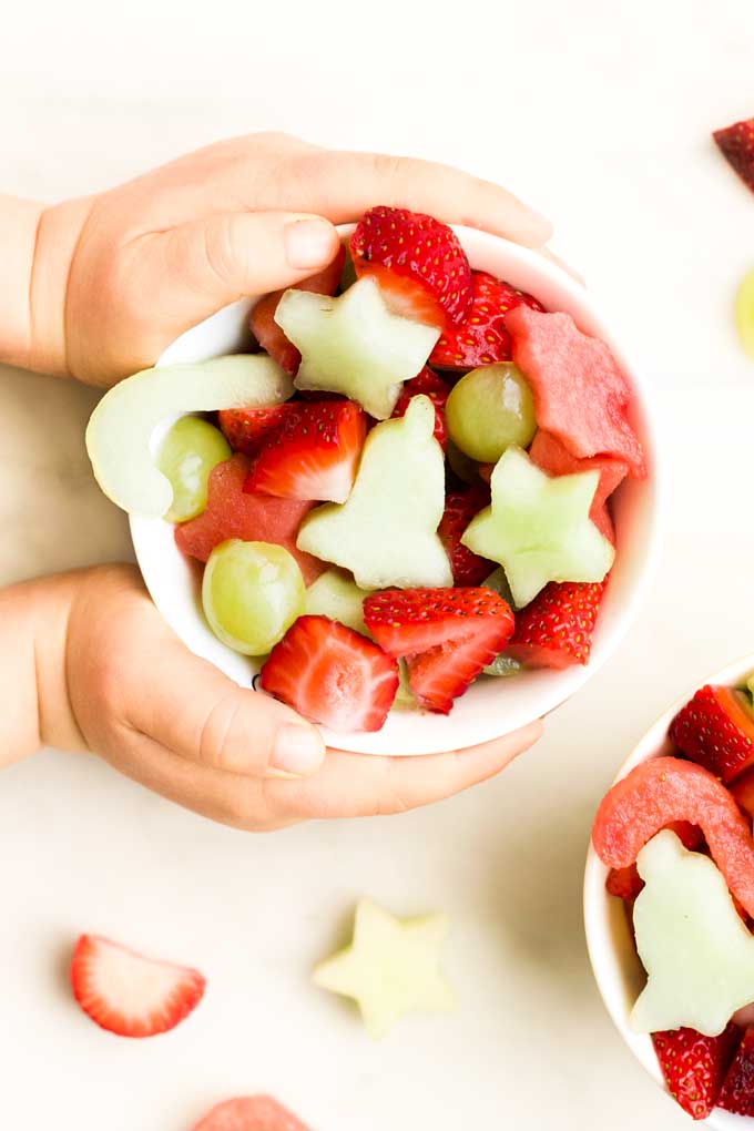 Child Holding a Bowl of Christmas Fruit Salad