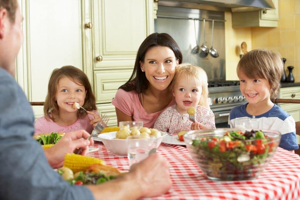 Family with Young Children Sitting at Table for Family Meal