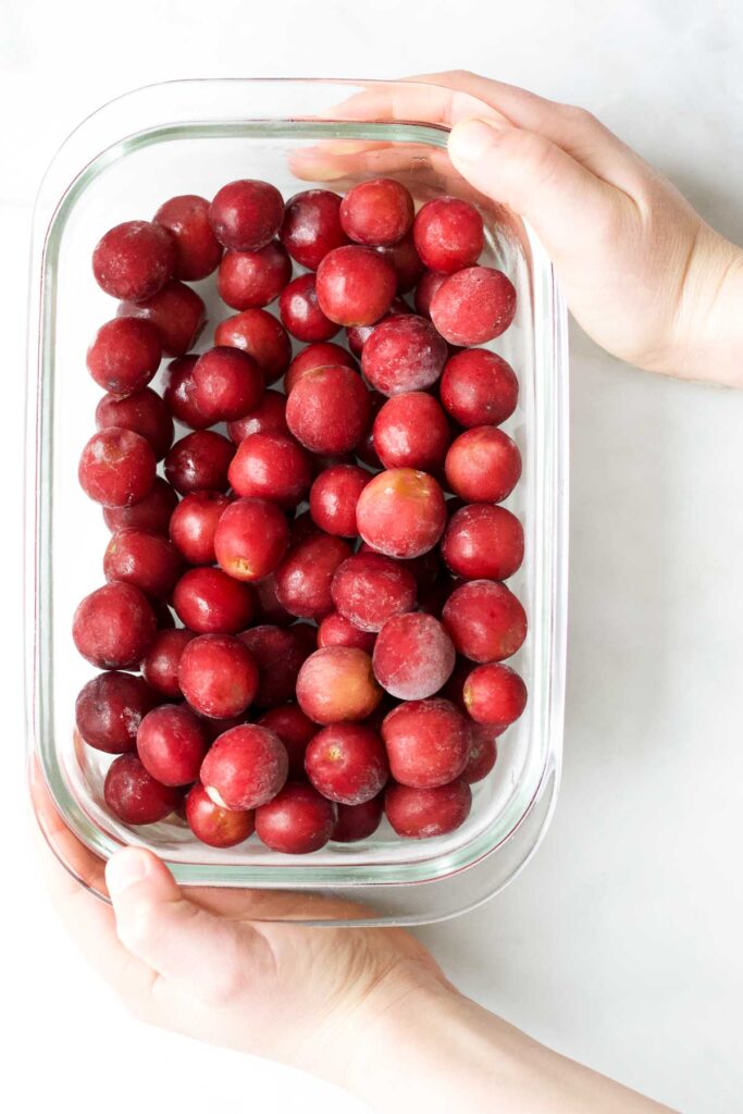 Chid Holding Container of Frozen Grapes