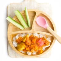 Fruity Chicken Curry on Baby Plate Served on Rice with a Side of Cucumber Sticks.