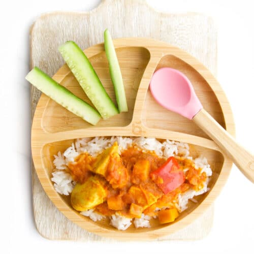 Fruity Chicken Curry on Baby Plate Served on Rice with a Side of Cucumber Sticks.