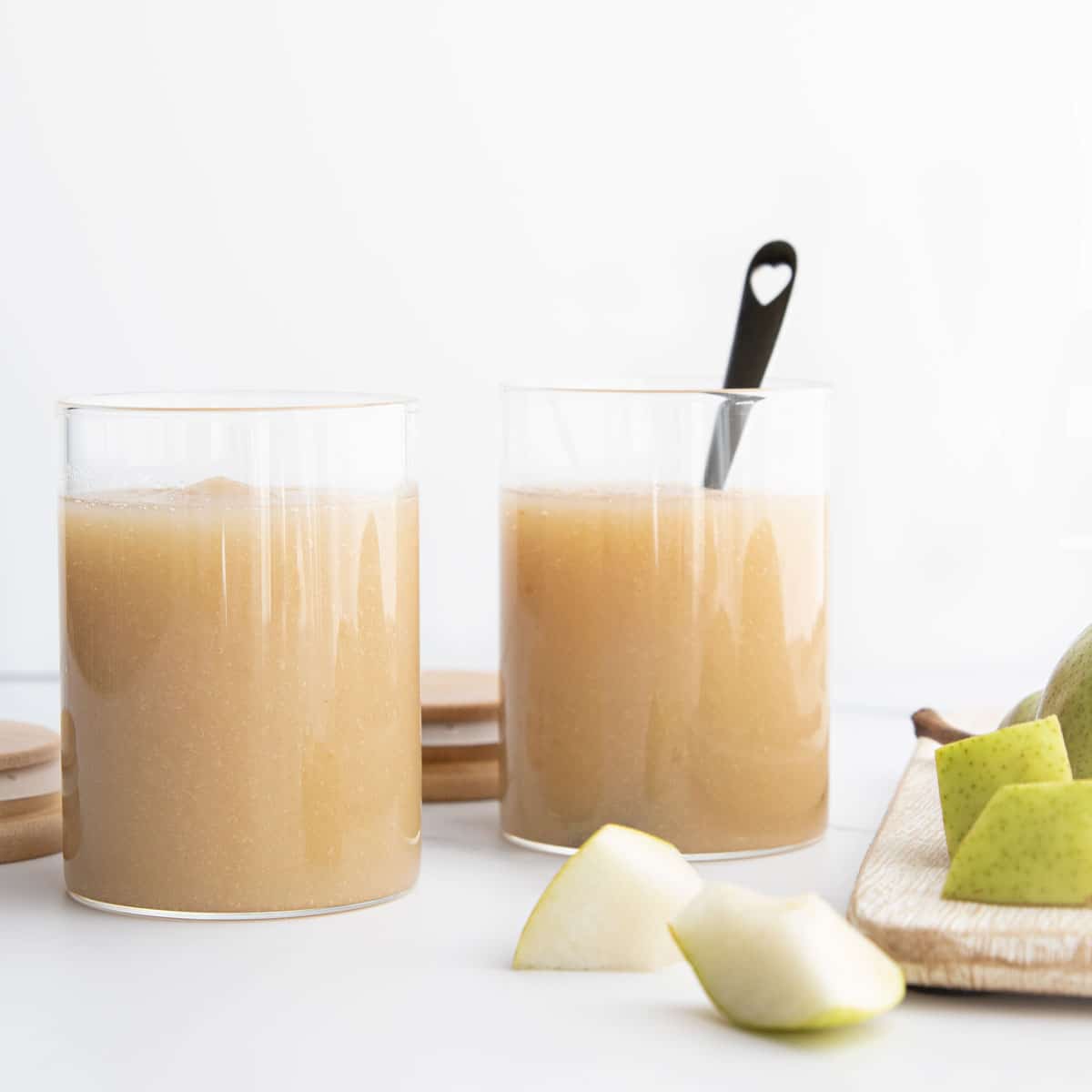 Pear Puree in Two Glas Jars with Chopped Pears in the Foreground.