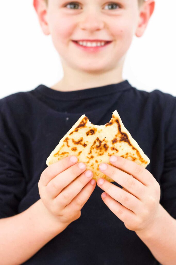 Child Holding Tattie Scone with Bite Taken Out