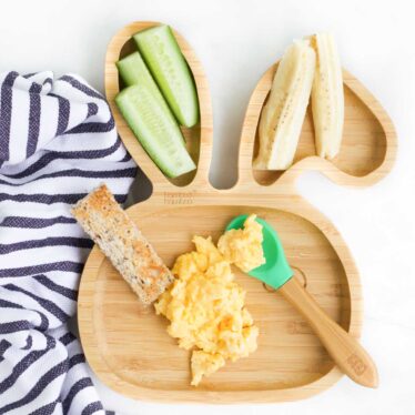 Top Down View of Scrambled Eggs on Baby Plate with Toast Finger, Cucumber and Banana