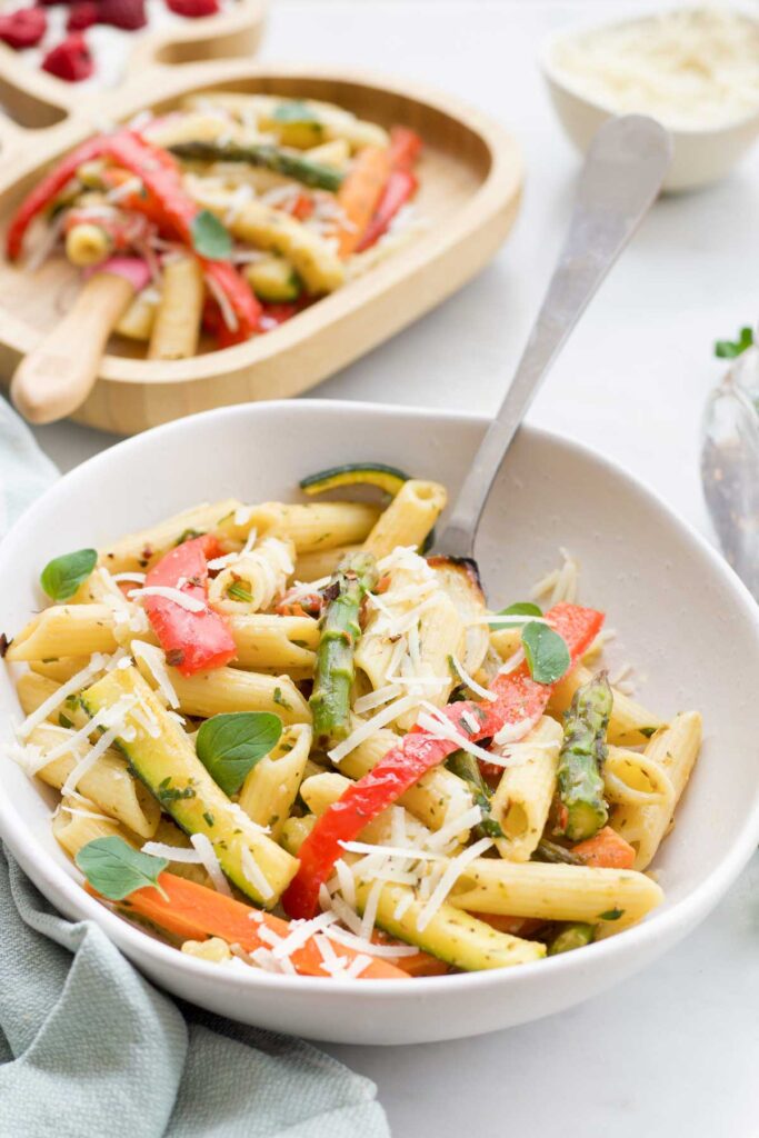 Bowl of Penne Pasta and Roasted Vegetables Scattered with Parmesan Cheese