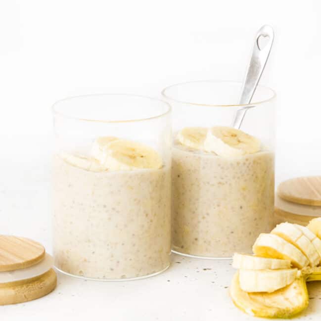 Two Glass Jars of Banana Chia Pudding Topped with Banana Slices.