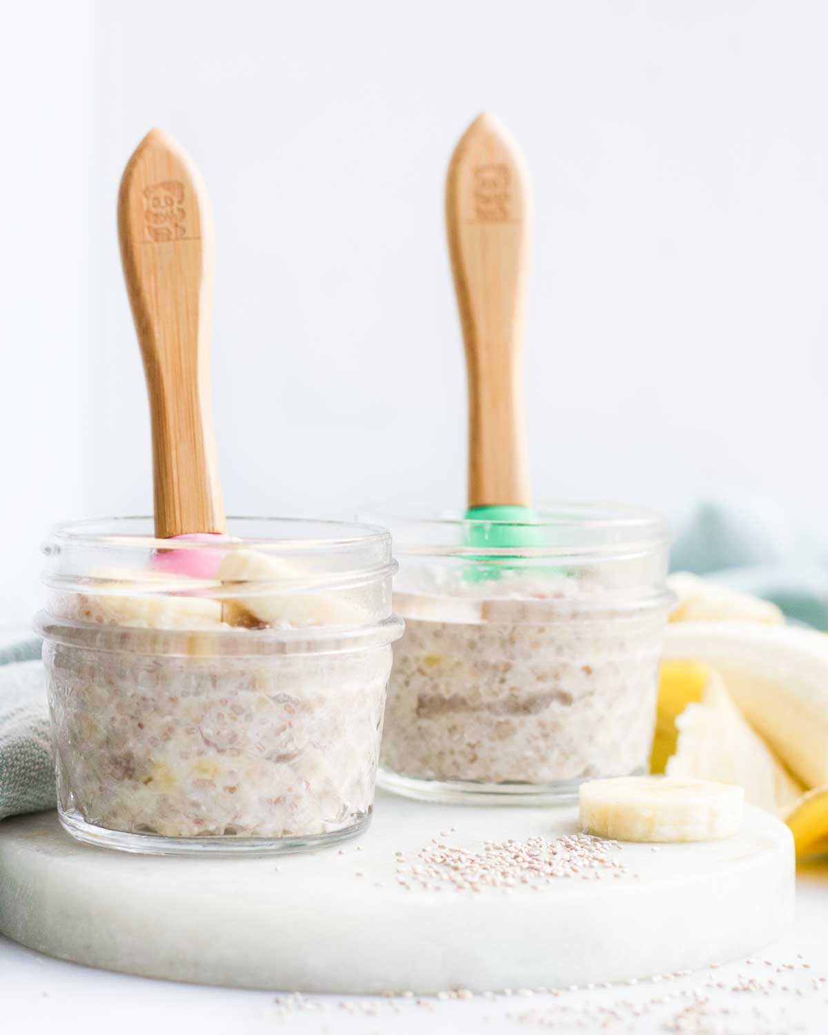 Side Shot of Two Small Glass Jars of Banana Chia Pudding with Spoons Sticking Out
