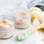 Two Small Glass Jars of Banana Chia Pudding with Spoon Sitting in Front