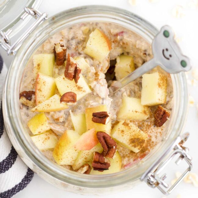 Overhead Shot Of Apple Overnight Oats in Mason Jar Topped with Apple Pieces and Pecan Nuts