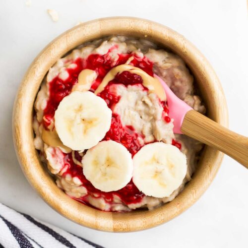 Banana Porridge in Baby Bowl Topped with Raspberries and Banana Slices