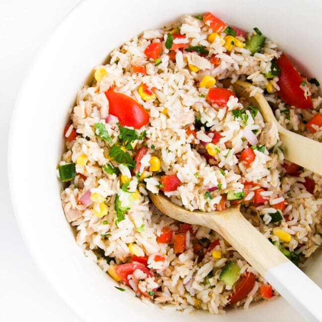 Top Down Shot of Tuna Rice Salad in Large White Bowl with Wooden Salad Spoons.