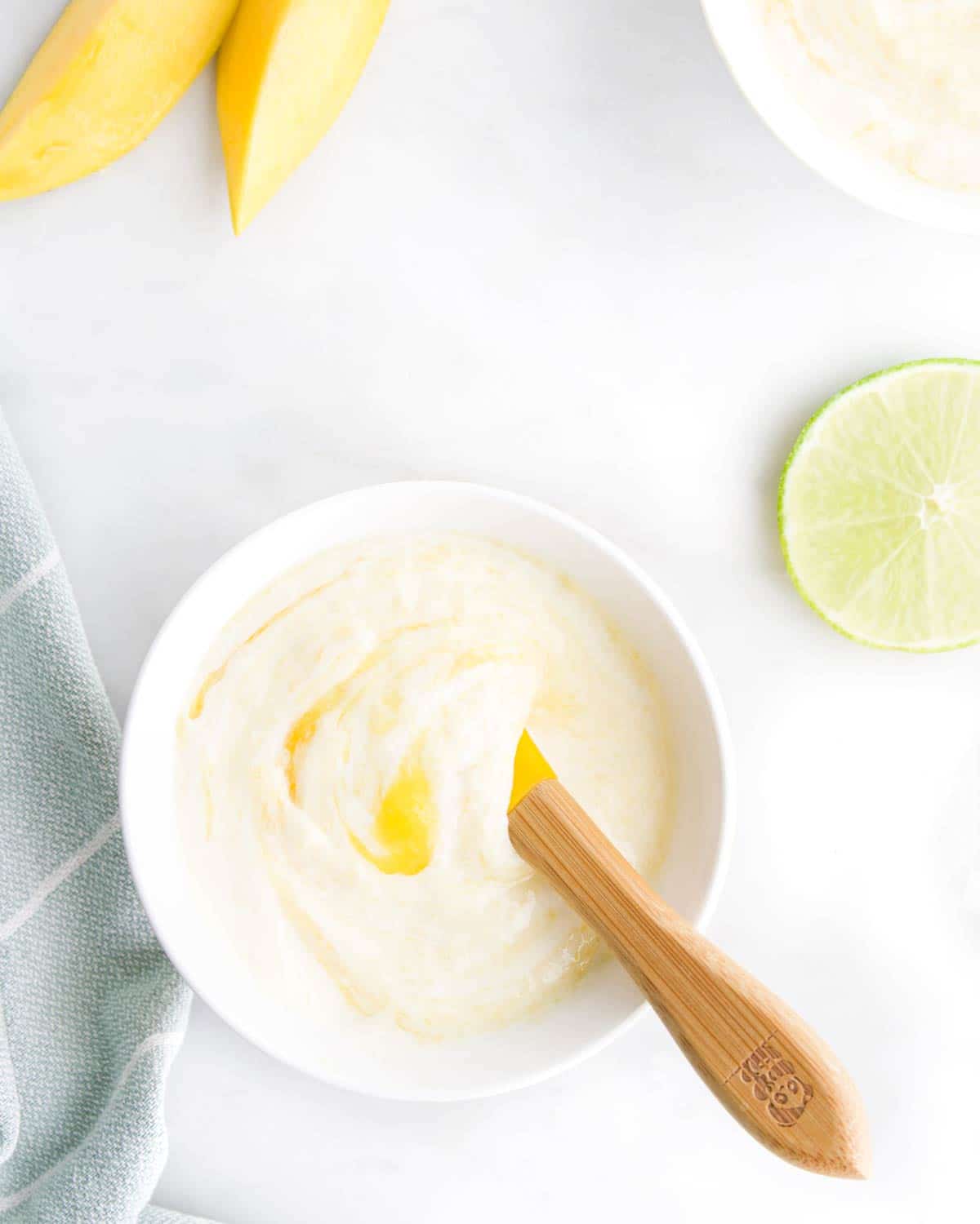 Mango Yogurt in Bowl with Slices of Lime and Mango in Background