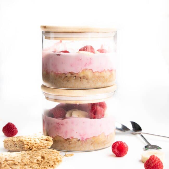 Two Stacked Glass Jars of Overnight Weetbix With Wheat Biscuits and Berries in Background