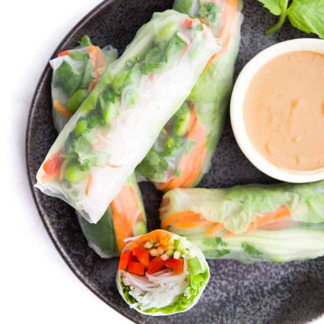 Vegetable Rice Paper Rolls on Black Plate with Dip. One cut in Half to Show Inside