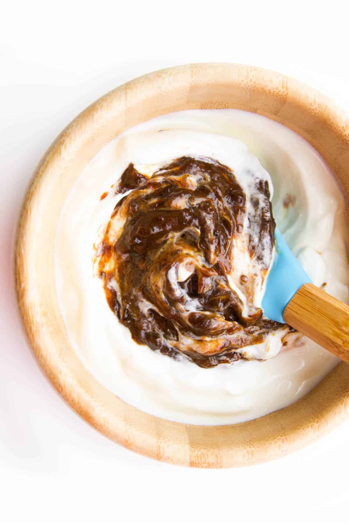Wooden Bowl Filled With Greek Yogurt Topped With Prune Puree.