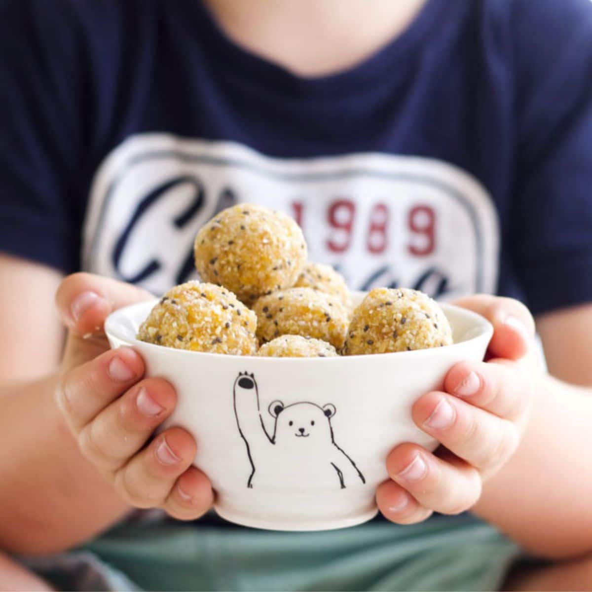 Child Holding Bowl of Apricot Bliss Balls. 