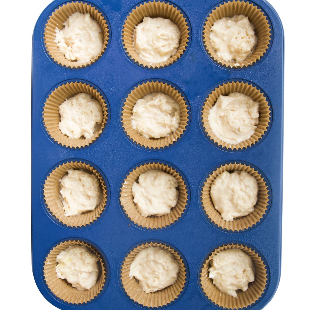 Small Amount of Muffin Batter Without Blueberries in Bottom of Muffin Tin Cups.