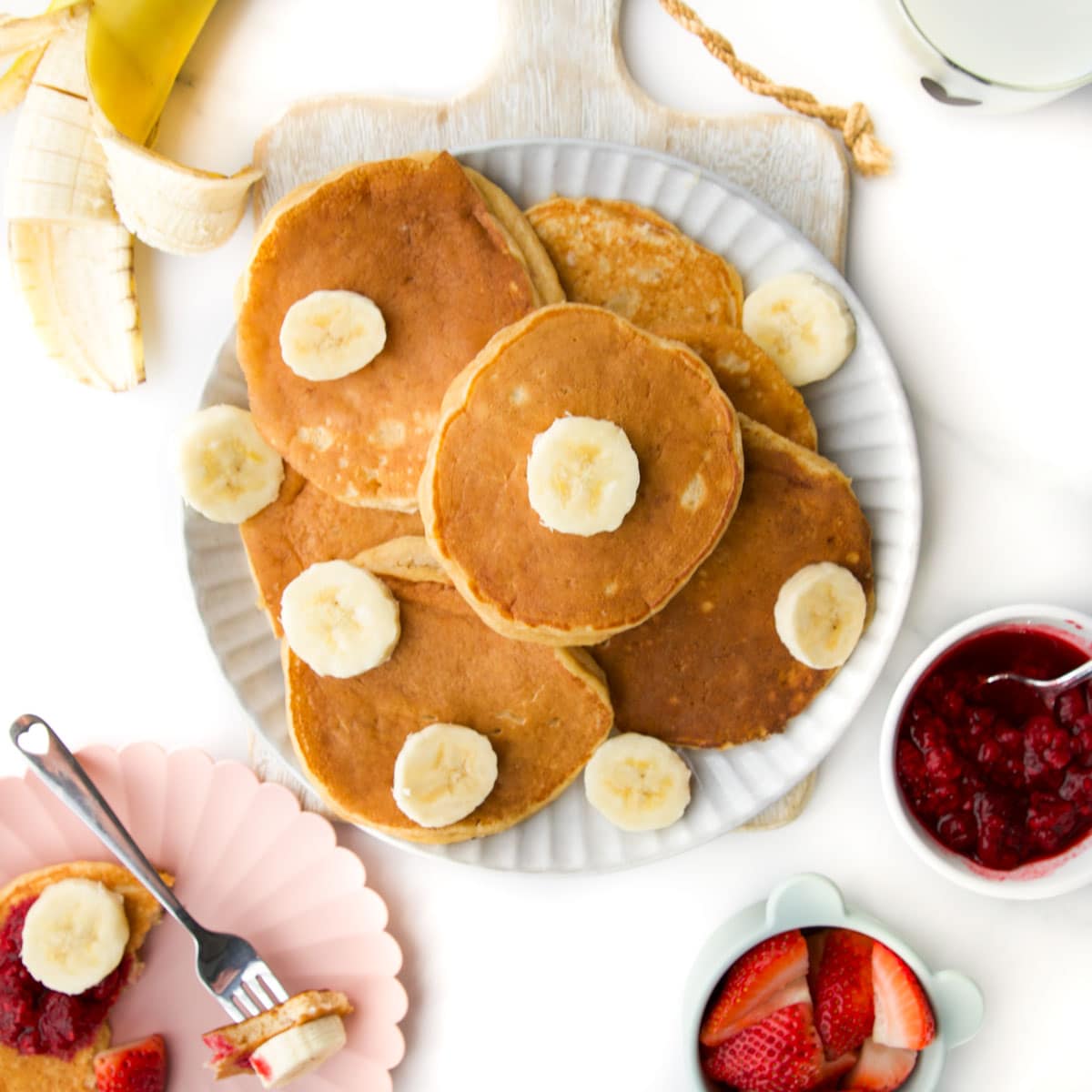 Banana Yogurt Pancakes on Plate with Slices of Banana Scattered.